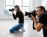 Mężczyzna i kobieta uczą się, jak zostać fotografem, ćwicząc z aparatami w studiu.