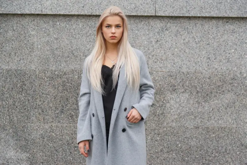 Blondynka w szarym płaszczu i czarnej koronkowej bluzce. Czerń idealnie podkreśla szarość, pokazując, jaki kolor pasuje do szarego ubrania.